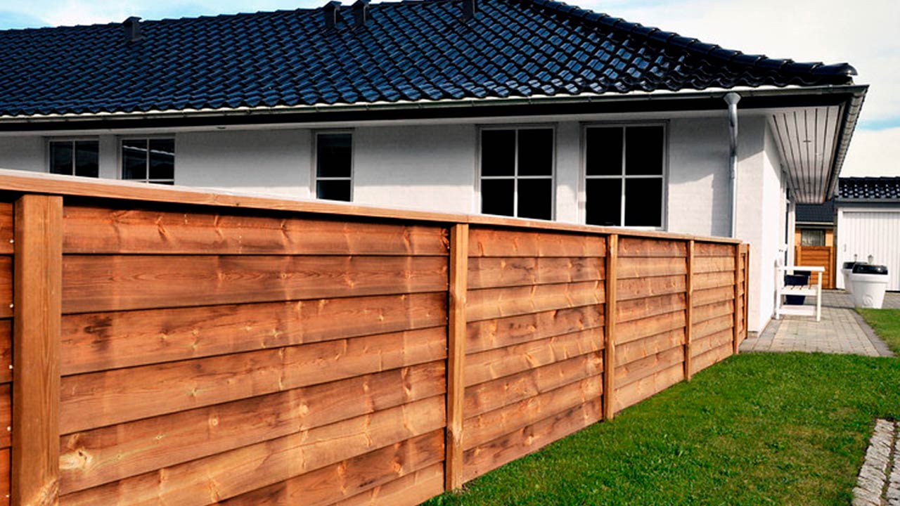 Lavt tr&aelig;hegn til villa lavet med systemhegn