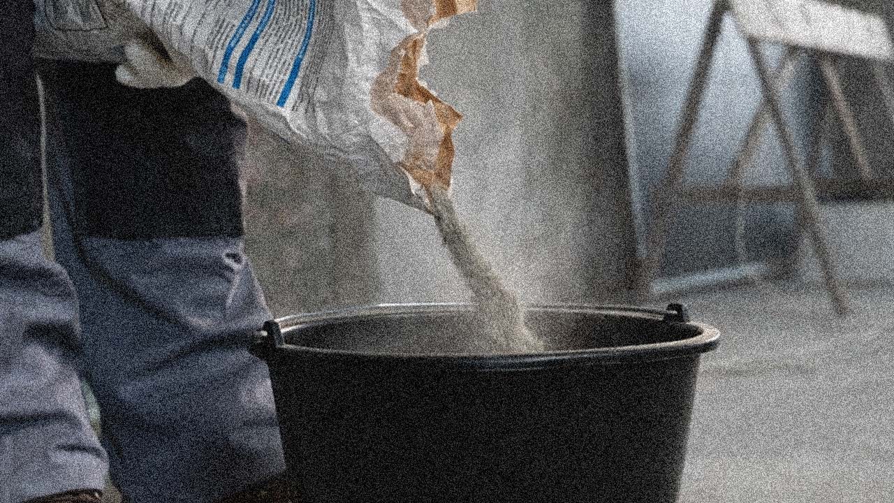 Cement til st&oslash;bning af gulv h&aelig;ldes i spand