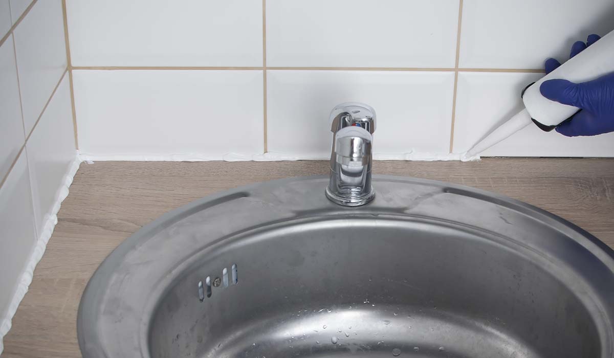 Hvid sanitetsfuge langs fliser ved h&aring;ndvask